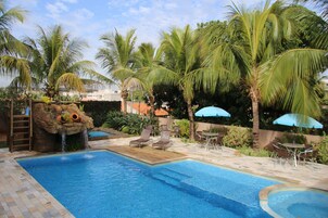 Una piscina al aire libre, sombrillas, sillones reclinables de piscina