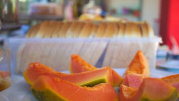 Un plato de papaya en rodajas y un recipiente blanco con pan.