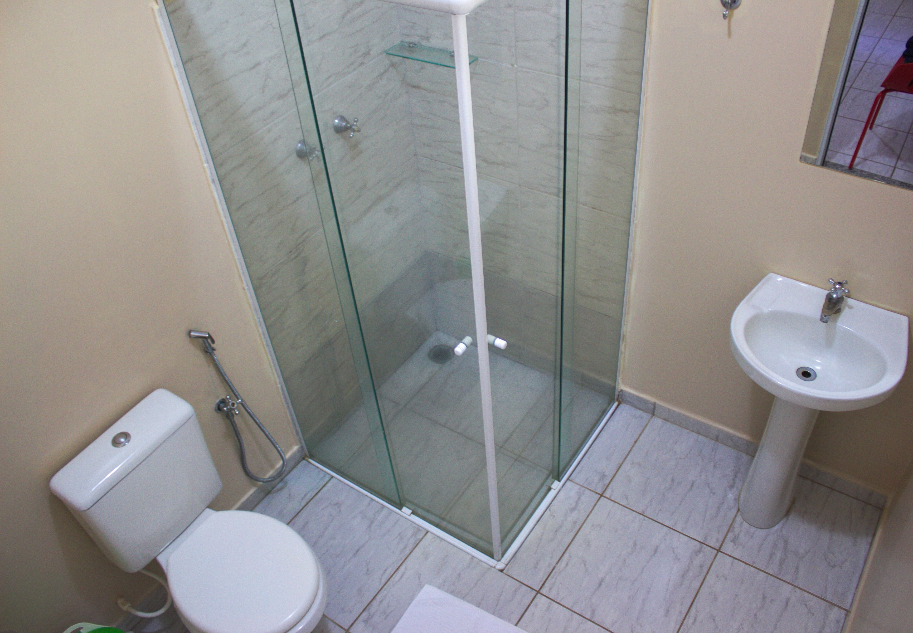 Un baño con ducha de vidrio, inodoro y lavamanos.