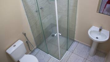 Un baño con ducha de vidrio, inodoro y lavamanos.