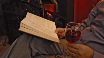 A person reading a book and holding a glass of red wine.