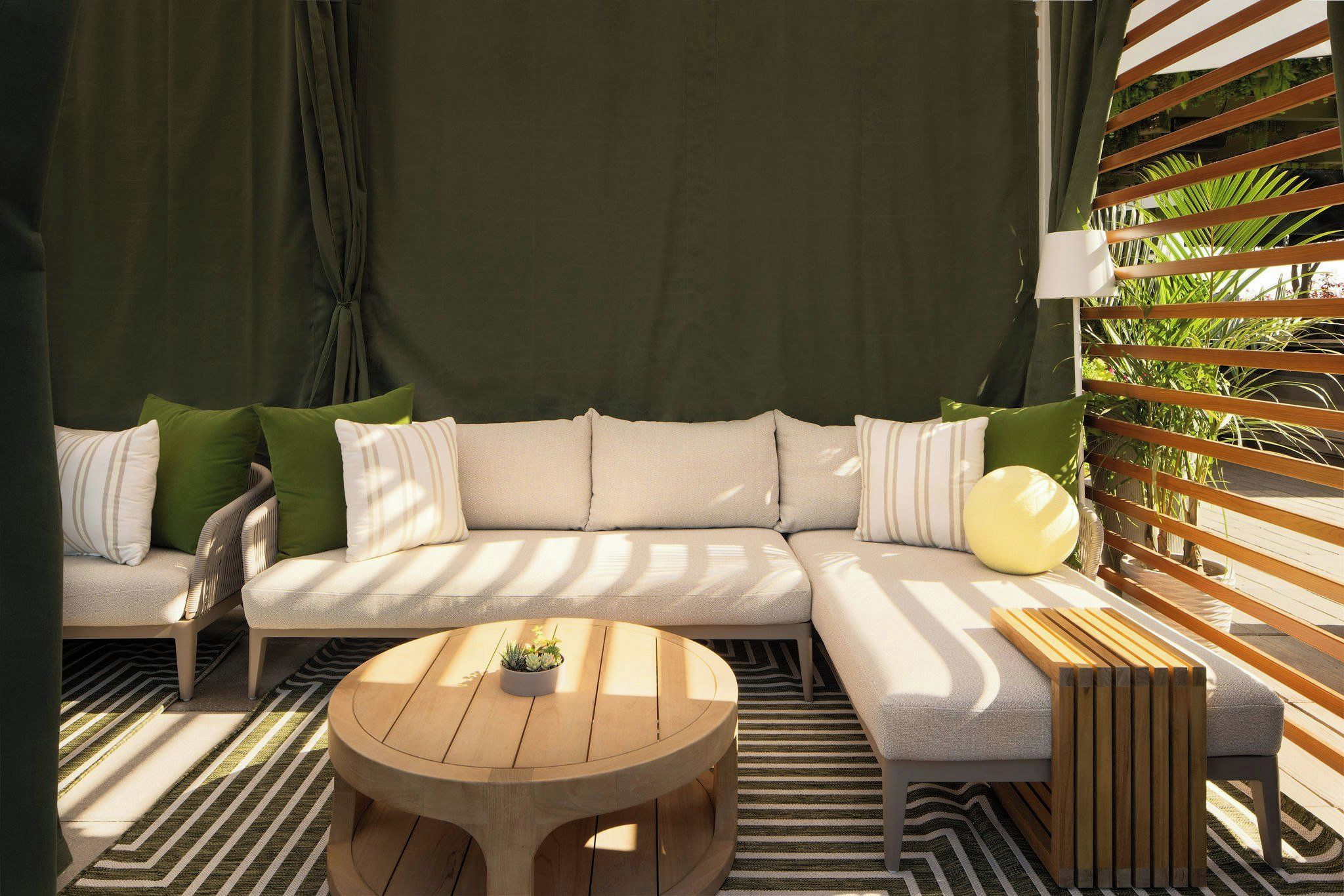 Un sofá modular con varios cojines, una mesa de centro redonda de madera y una alfombra a rayas.