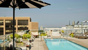 A rooftop pool with lounge chairs, a glass balustrade, and a view of the city skyline. - Halcyon, a hotel in Cherry Creek, Denver (Denver)
