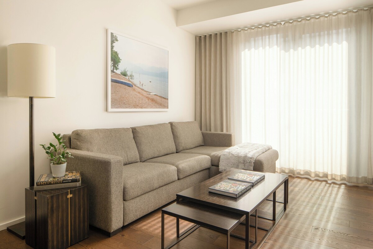 A living room with a sofa, a coffee table, a lamp, a plant, and a painting on the wall.