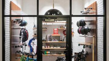 Una habitación con separador de vidrio, bicicletas y estantes con cascos y equipo.