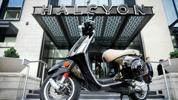 Een motorfiets geparkeerd voor een gebouw met een bord waarop 'HALCYON' staat.