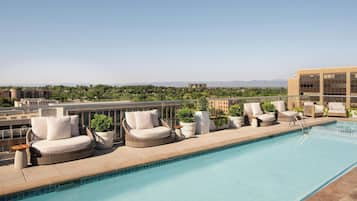 A rooftop pool area with lounge chairs and a clear view of the surrounding landscape.