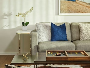 A living room with a sofa, a small side table, a coffee table, and a framed picture on the wall.