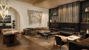 A modern living room with a fireplace, leather sofas, a coffee table, and a dining area with a wooden table and chairs. - Halcyon, a hotel in Cherry Creek, Denver (Denver)
