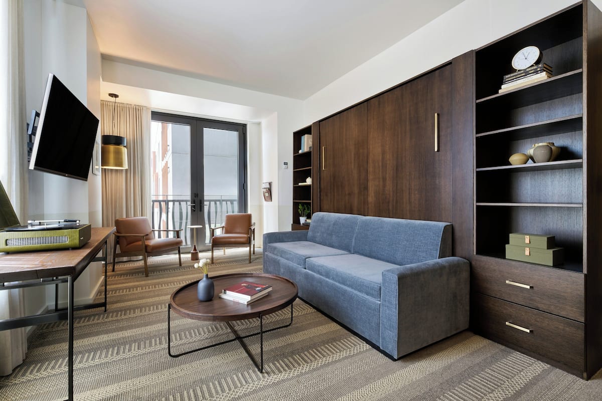 A modern living room with a sofa, coffee table, TV, and a large wardrobe with shelves.