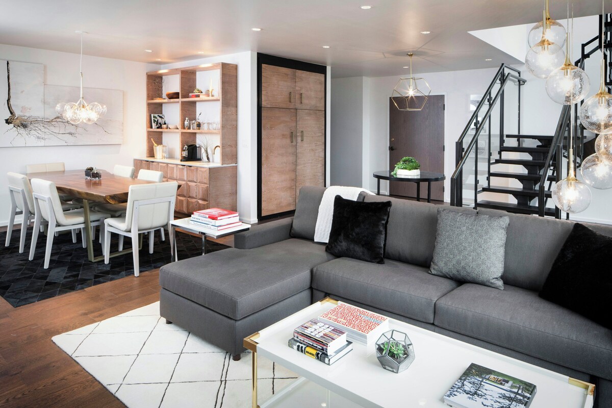 Una sala de estar moderna con un sofá modular, una mesa de comedor y libros.