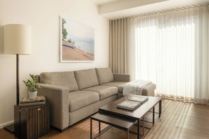 Un salon avec un canapé, une table basse, une lampe, une plante et un tableau accroché au mur.