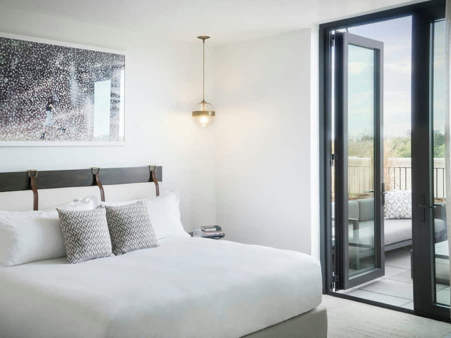 Un dormitorio con cama, mesita de noche, lámpara colgante y puerta corrediza de cristal a un espacio exterior.