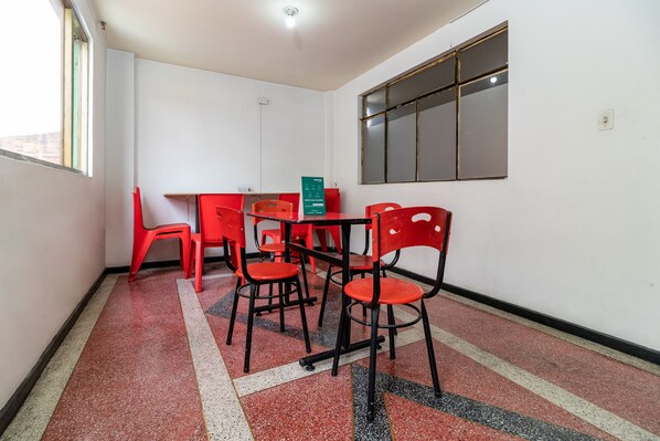 A room with a tiled floor, a table with chairs, and a window.