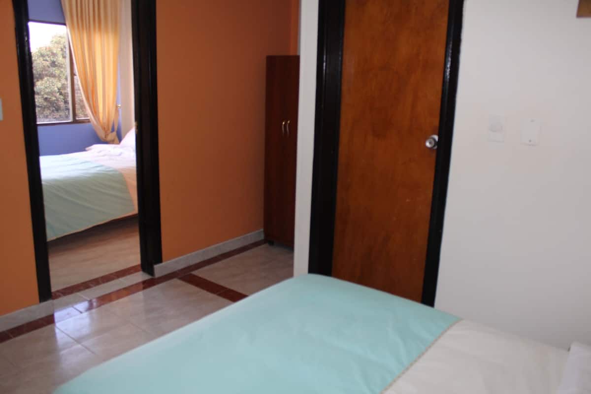 Un dormitorio con una cama, un armario de madera y una puerta que da a otra habitación.