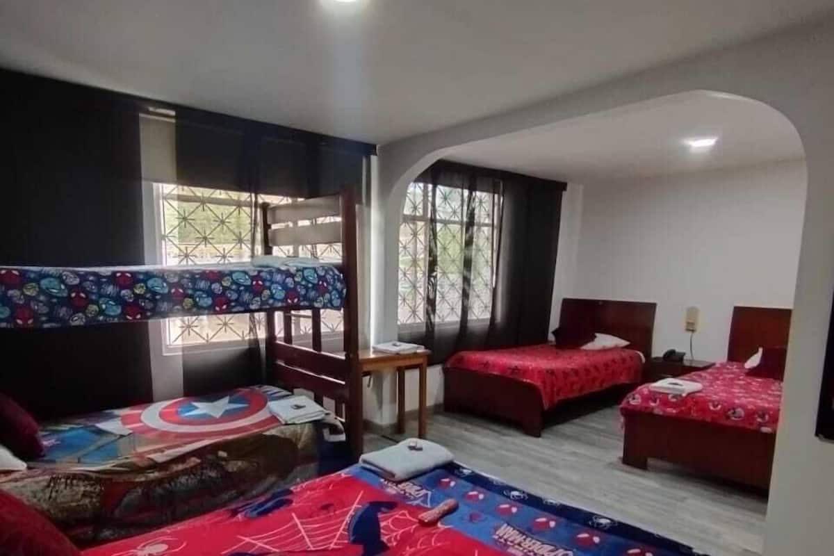 Une chambre avec des lits superposés, un bureau et une fenêtre.