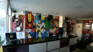 A reception desk with comic book-style artwork on the wall and a modern, clean interior design. - Hotel Comic City (Bogotá)