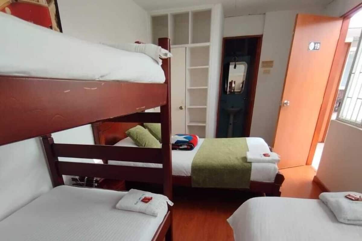 Une chambre de dortoir avec des lits superposés, une armoire et une porte portant le numéro 19.