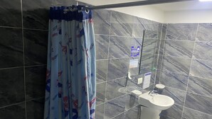 A bathroom with a shower curtain featuring a Spider-Man pattern, a toilet, and a sink with a marble backsplash. - Hotel Comic City (Bogotá)