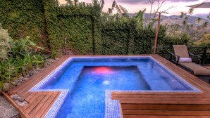 Ein Whirlpool mit einer gefliesten Kante, umgeben von einer Holzterrasse und einer Steinterrasse.