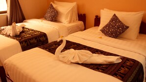 Une chambre d’hôtel avec deux lits, chacun étant équipé de draps blancs et d’oreillers à motifs.