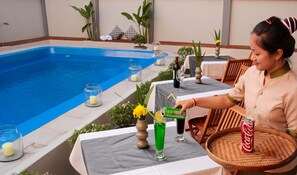 A poolside area with tables, chairs, and a dining setup.