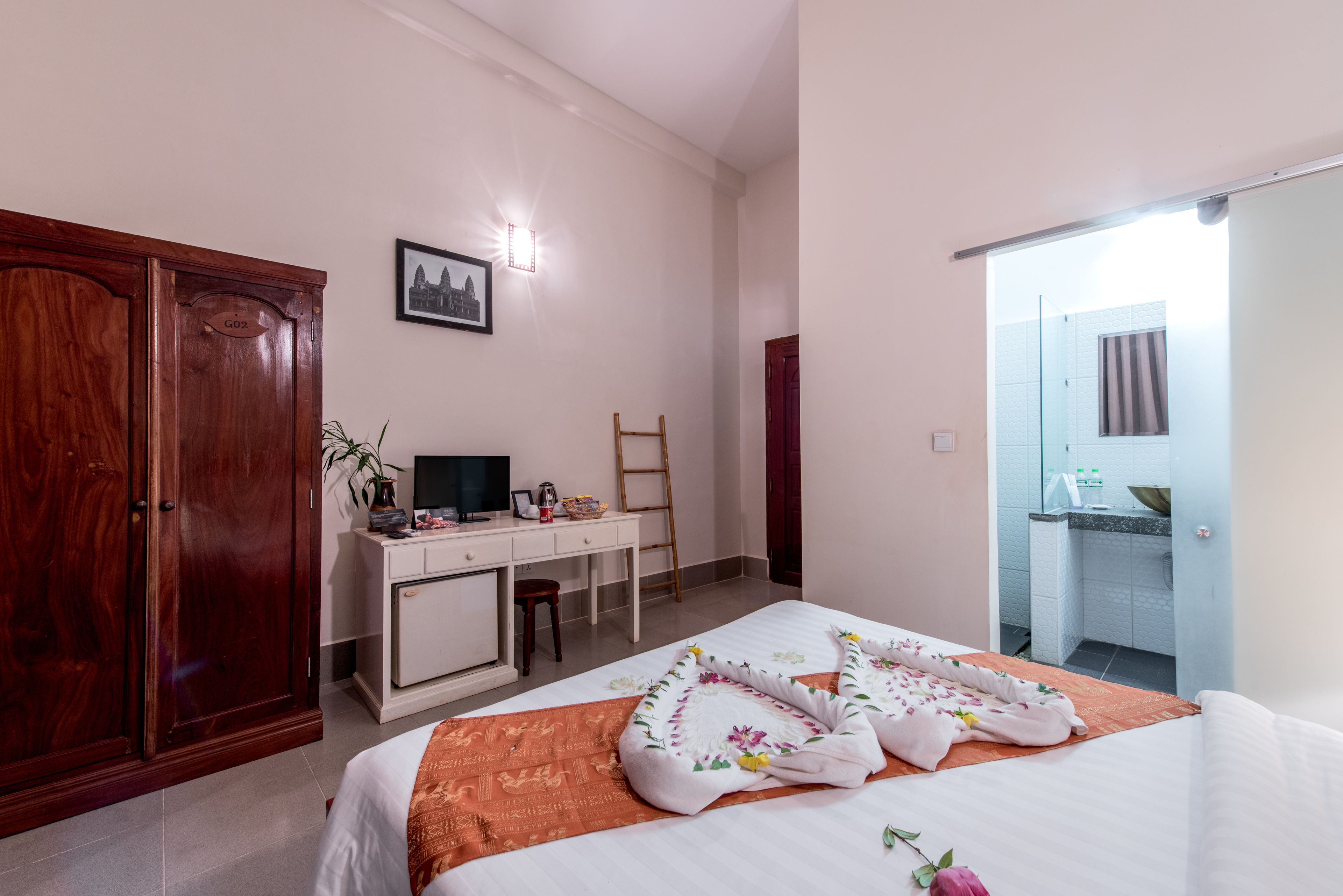 Un dormitorio con cama, escritorio, armario y baño visible a través de una puerta abierta.