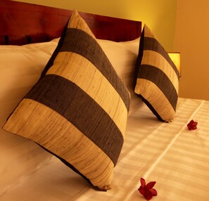 A bed with striped pillows and a red flower on the bedspread.