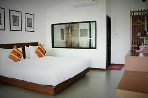 Habitación de hotel con una cama grande, cabecera de madera y un ventanal con vista al baño.