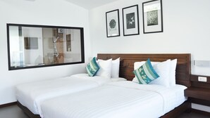 Ein Hotelzimmer mit einem großen Bett, einem hölzernen Kopfteil und einem großen Fenster. Über dem Bett hängen drei gerahmte Bilder an der Wand.