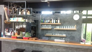 Eine Bar mit Regalen voller Flaschen, Gläsern und einer Wanduhr.