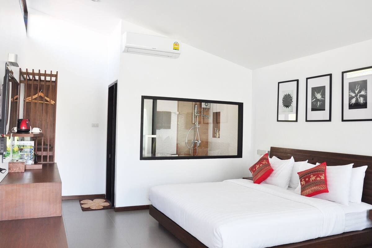 Une chambre d’hôtel avec un lit, un bureau en bois, un miroir et trois tableaux encadrés accrochés au mur.