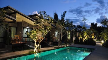 A modern hotel with a swimming pool, outdoor seating, and a well-maintained garden.