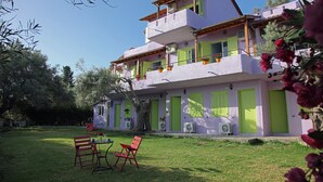 A two-story building with a balcony, a lawn, and outdoor furniture. - Summer House Louisa (Lefkada)