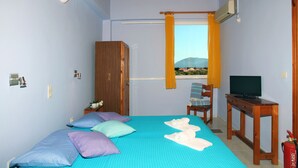 A bedroom with a bed, pillows, a wooden wardrobe, a desk with a television, and a window with curtains. - Summer House Louisa (Lefkada)