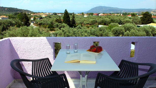 A table with two chairs, an open book, and a bowl of fruit. - Summer House Louisa (Lefkada)