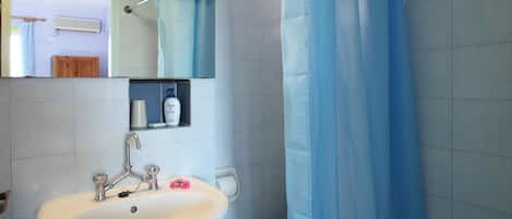 Baño con lavamanos, espejo y cortina de ducha.