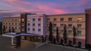 Um hotel Fairfield Inn & Suites Marriott com design moderno, destacando uma entrada imponente e um estacionamento.