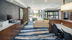 A modern office space with a long reception desk, a large window, and a blue patterned carpet. - Fairfield Inn & Suites by Marriott Edmonton North (Edmonton)
