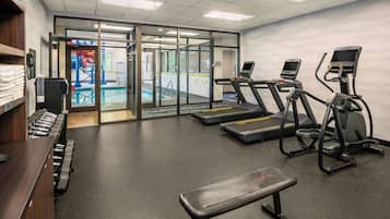 A gym with treadmills, a bench, and dumbbells.