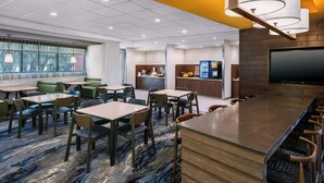 A modern hotel lobby with a bar area, seating arrangements, and a kitchen in the background. - Fairfield Inn & Suites by Marriott Edmonton North (Edmonton)