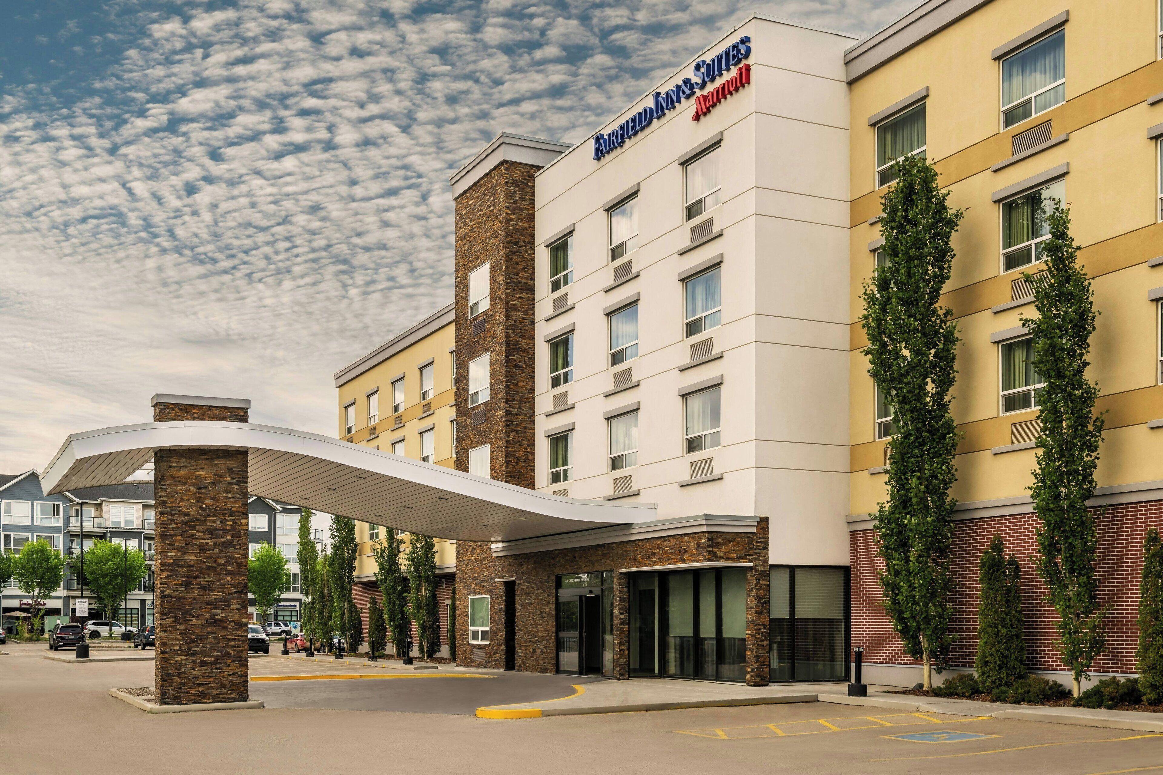 A hotel with a modern design, featuring a prominent entrance with a covered walkway, multiple floors, and a brick facade.
