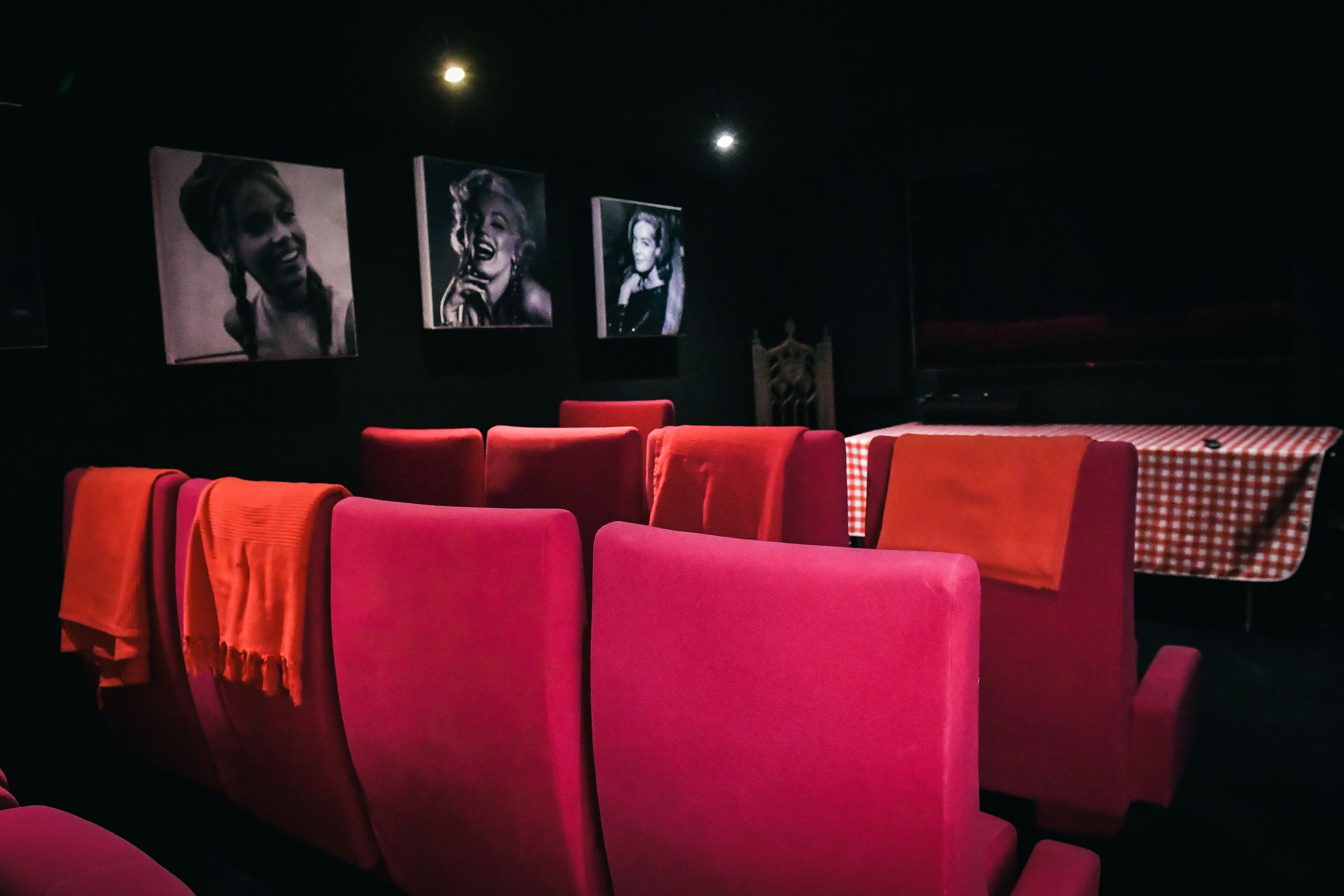 Une salle de cinéma avec des sièges rouges et une table recouverte d’une nappe à carreaux.