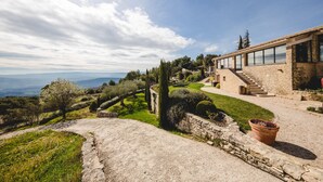 A stone building with a modern glass extension, a stone staircase, and a view of the landscape.
