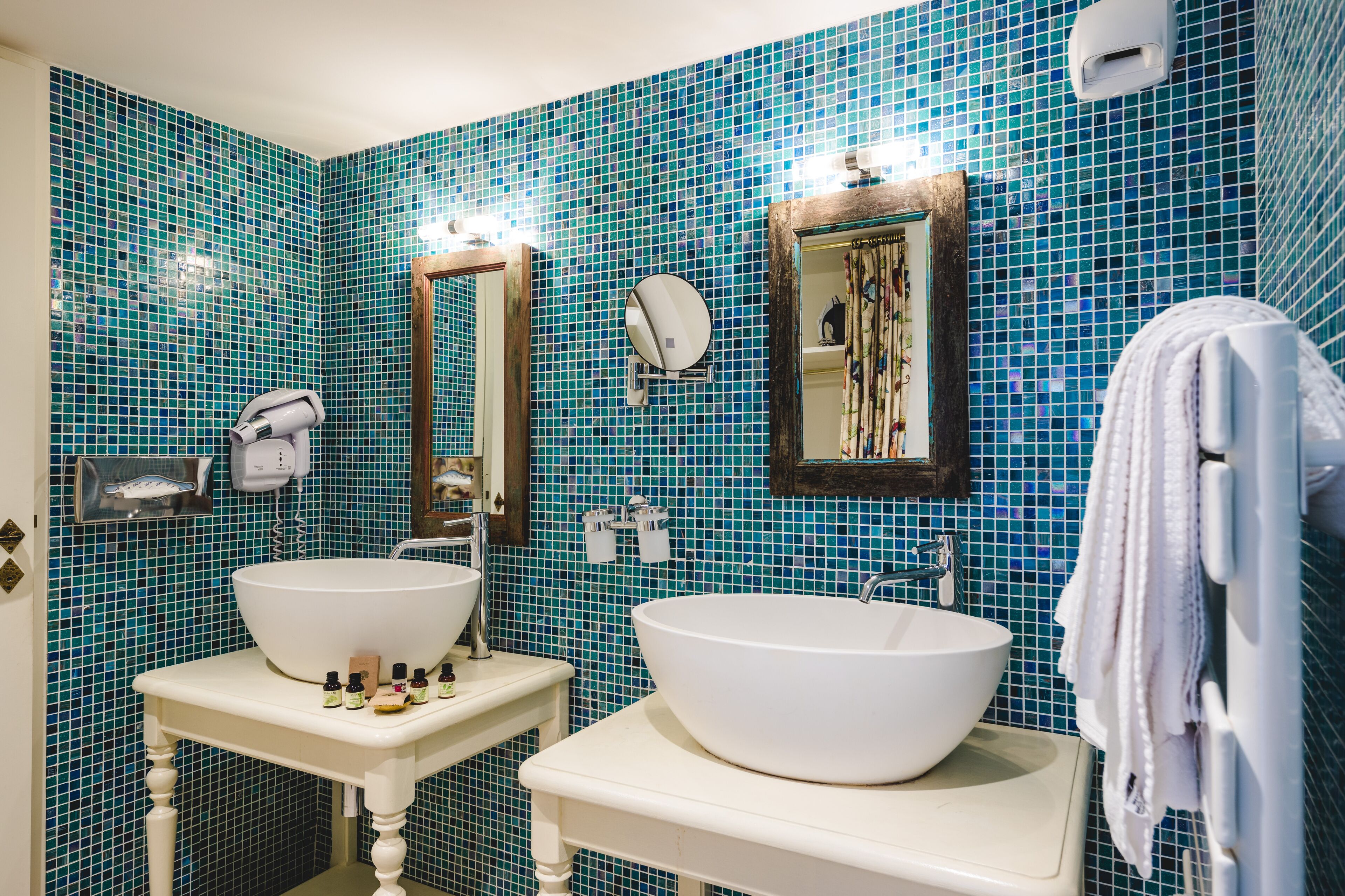 A bathroom with two white sinks, a mirror, and a towel rack.