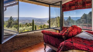A room with a large window offering a scenic view of the countryside.
