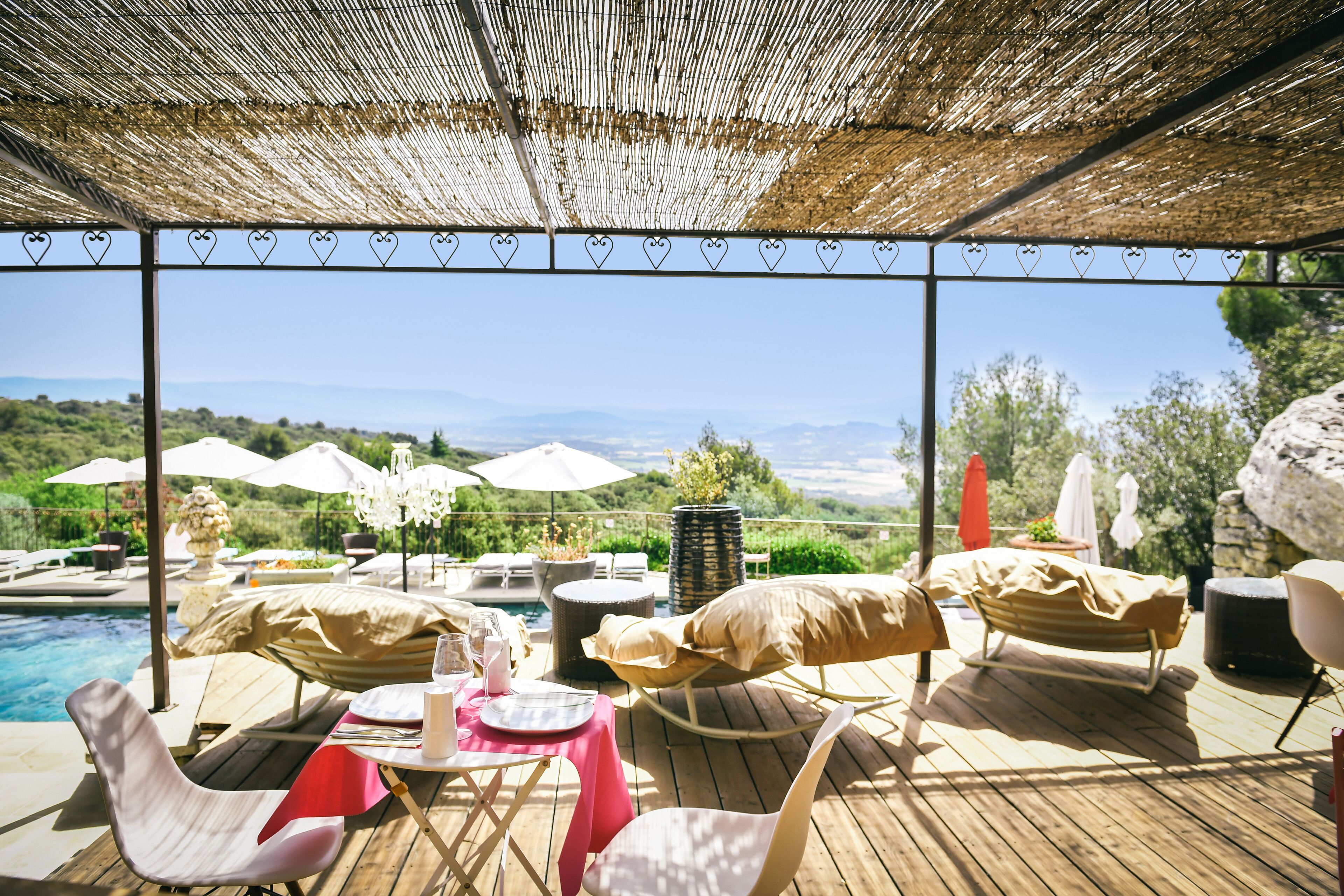 An outdoor pool area with lounge chairs, umbrellas, and a table set for dining.