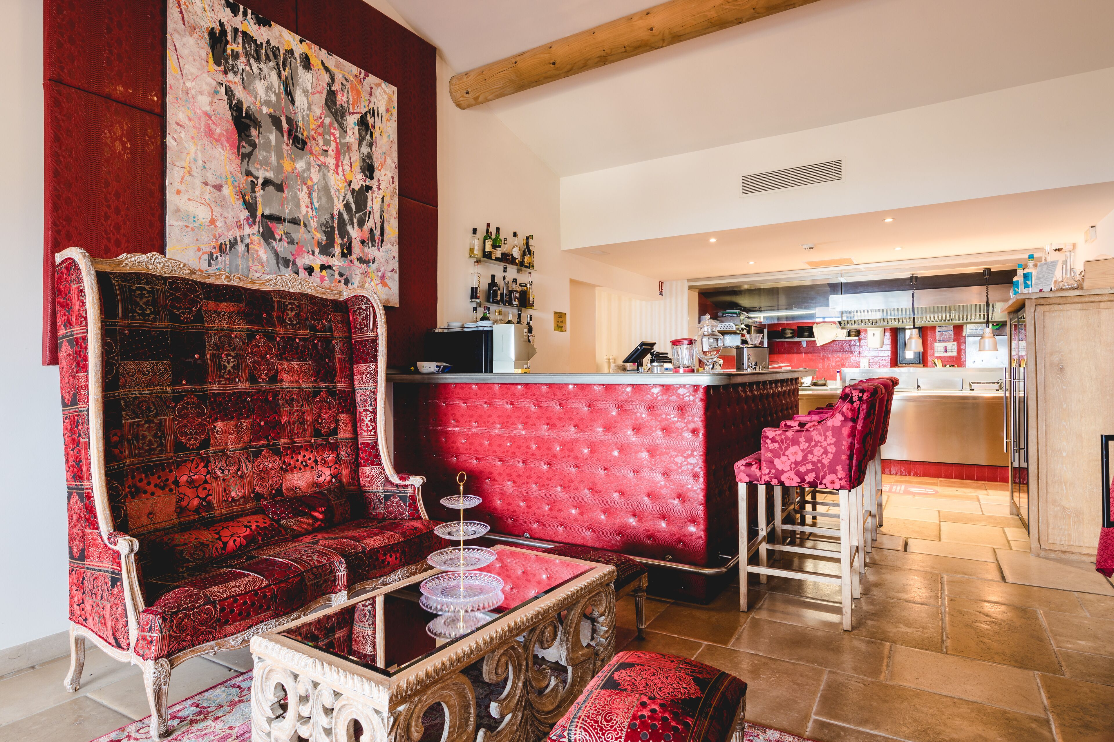 A living room with a red sofa, a coffee table, and a bar area in the background.