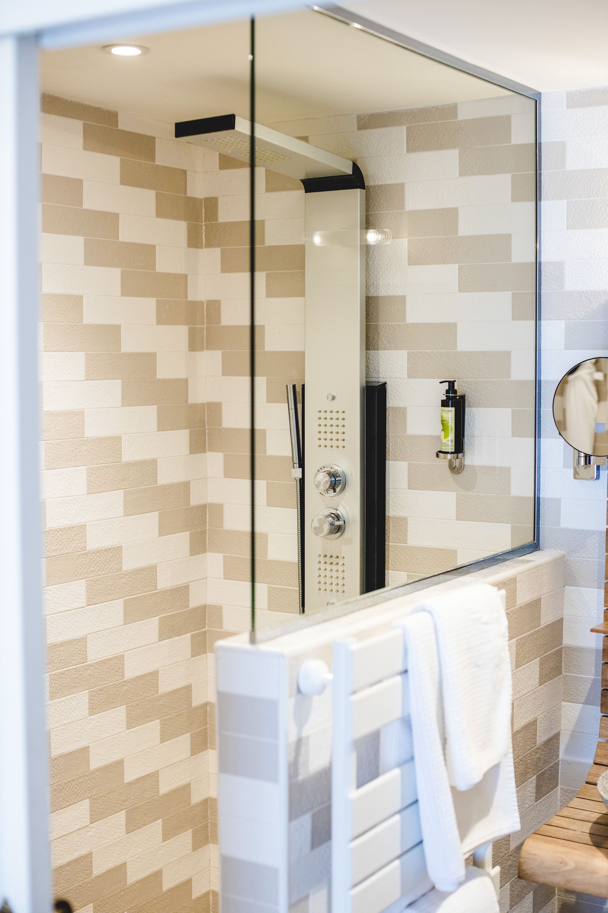 A bathroom with a shower, a mirror, and a towel rack.