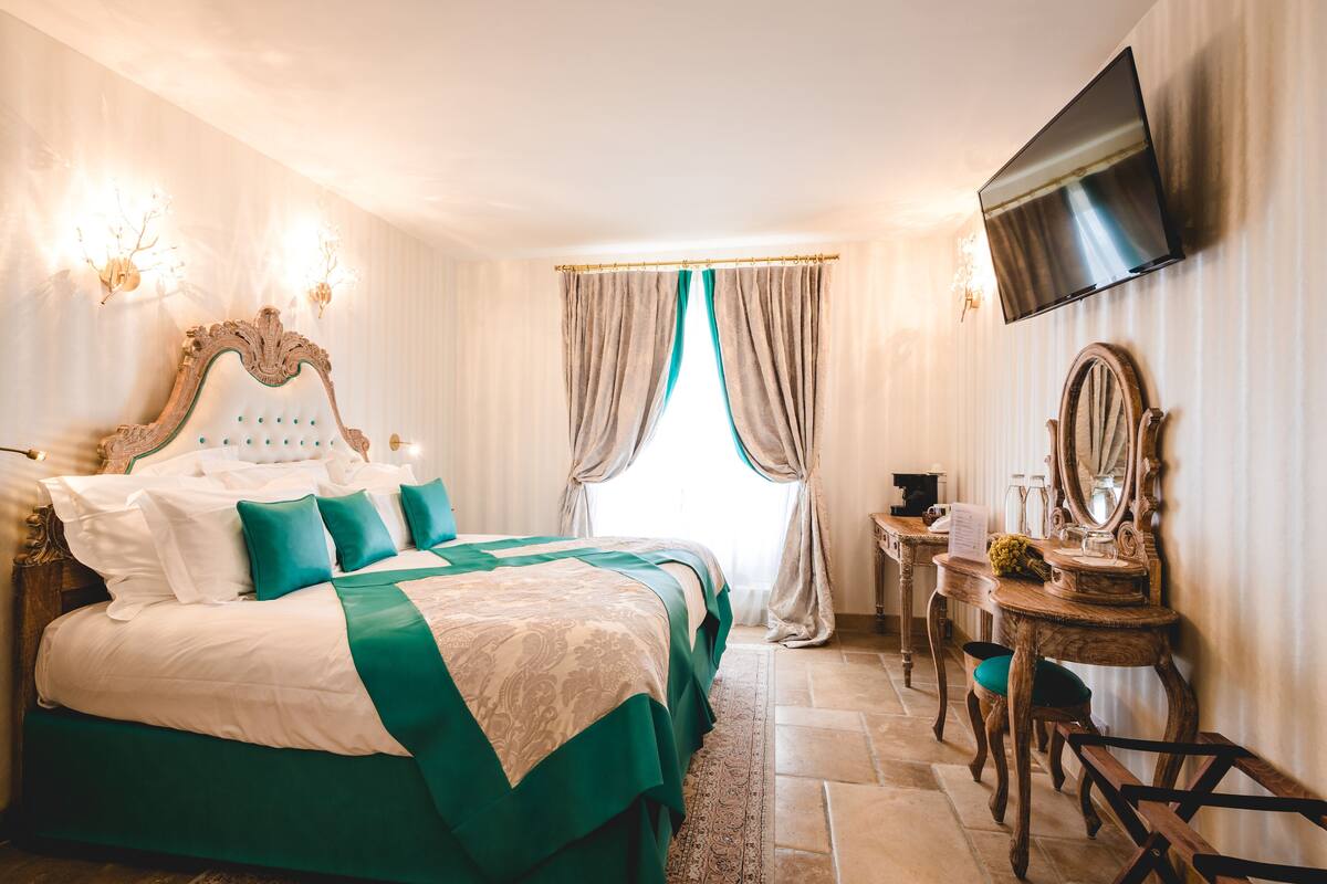 Une chambre d’hôtel avec un grand lit, un bureau doté d’un miroir et un téléviseur fixé au mur.